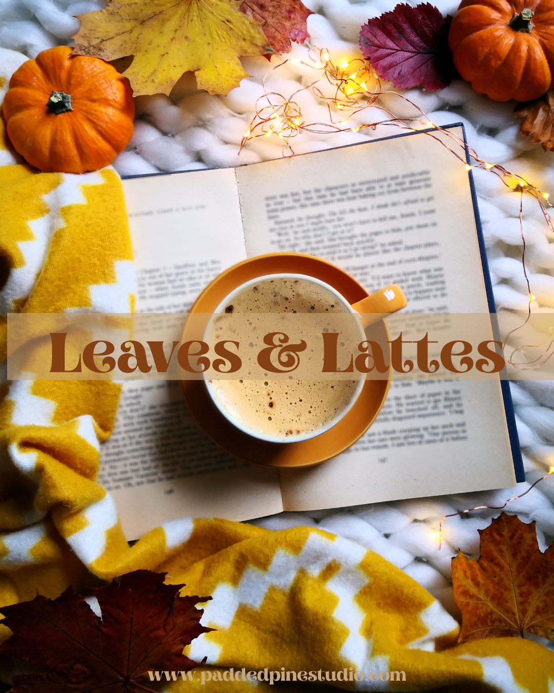 A cozy autumn flat-lay featuring a cup of coffee or latte in a saucer on an open book, surrounded by yellow and orange pumpkins, colorful fall leaves, a yellow and white chevron knit blanket, and warm fairy lights. A translucent banner across the center reads 'Leaves & Lattes' with a website URL at the bottom.