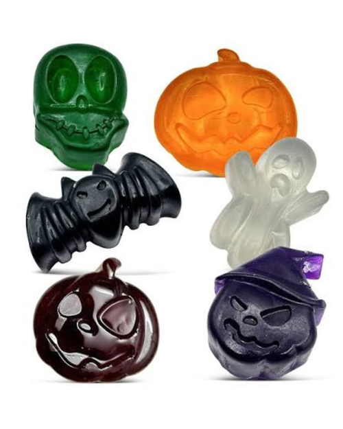 Six Halloween-themed translucent bath bombs arranged on a white background: a green skull, an orange jack-o'-lantern, a black bat, a white ghost, a dark brown pumpkin, and a dark purple witch hat pumpkin.