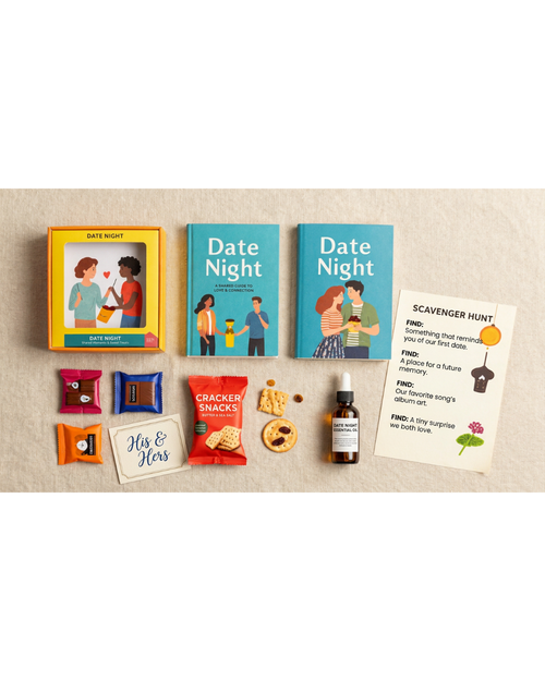 A flat-lay of a 'Date Night' themed gift set on a textured beige fabric background. The set includes two copies of the 'Date Night' book, a yellow 'Yes & You' card, a 'Scavenger Hunt' card, chocolate-covered sticks, a bottle of essential oil, cookies, and a small t-shirt.
